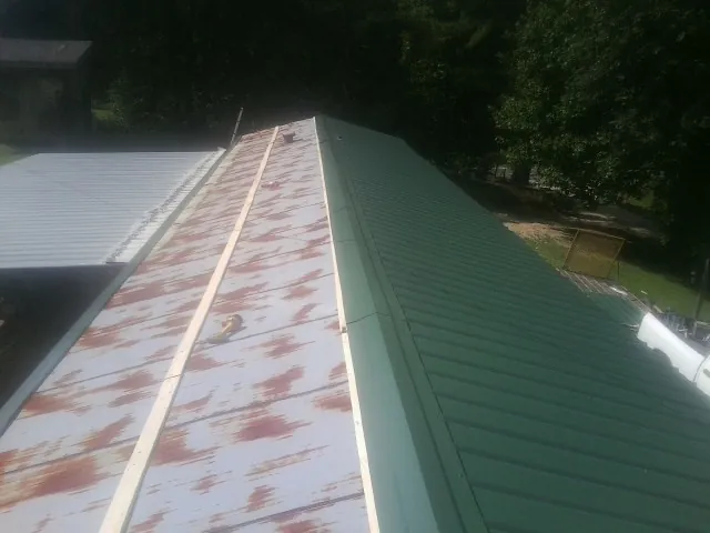 Old rusted panels beside newly installed green metal roofing — Wind Damage Roof Repair by Roofing Brothers in Mendenhall