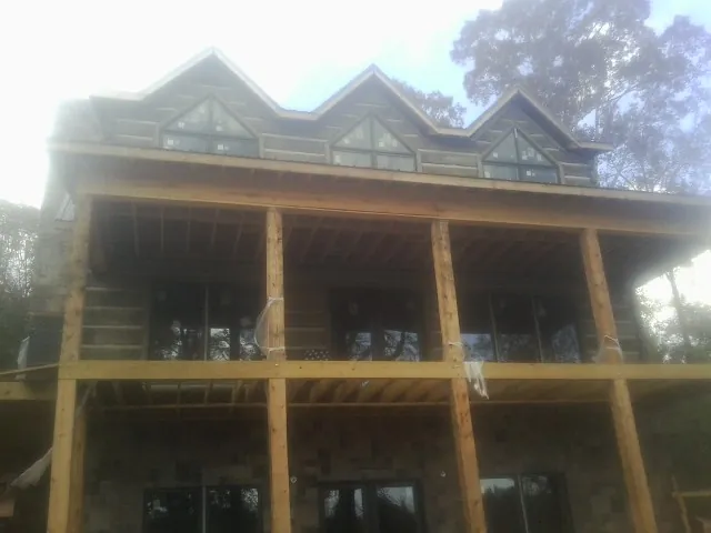 Dormers and porch framing on a large log home under construction — Roof Coating work by our crew in Mendenhall