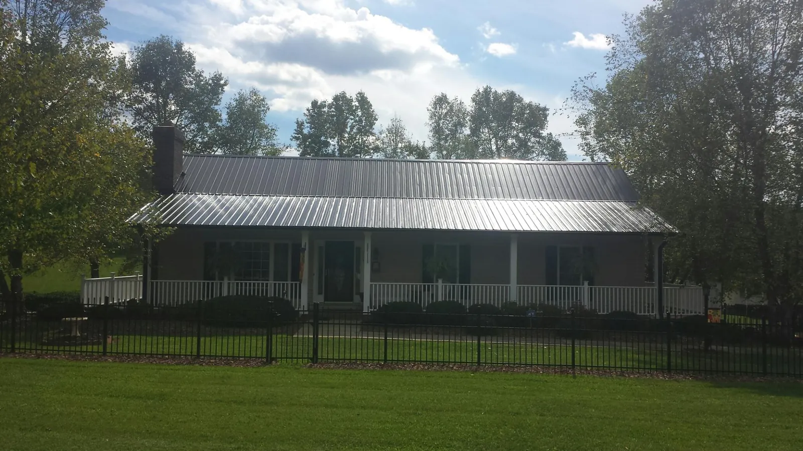 Gray metal roof on a brick ranch with a full width front porch — Gutter Guard Installation work by our crew in Mendenhall