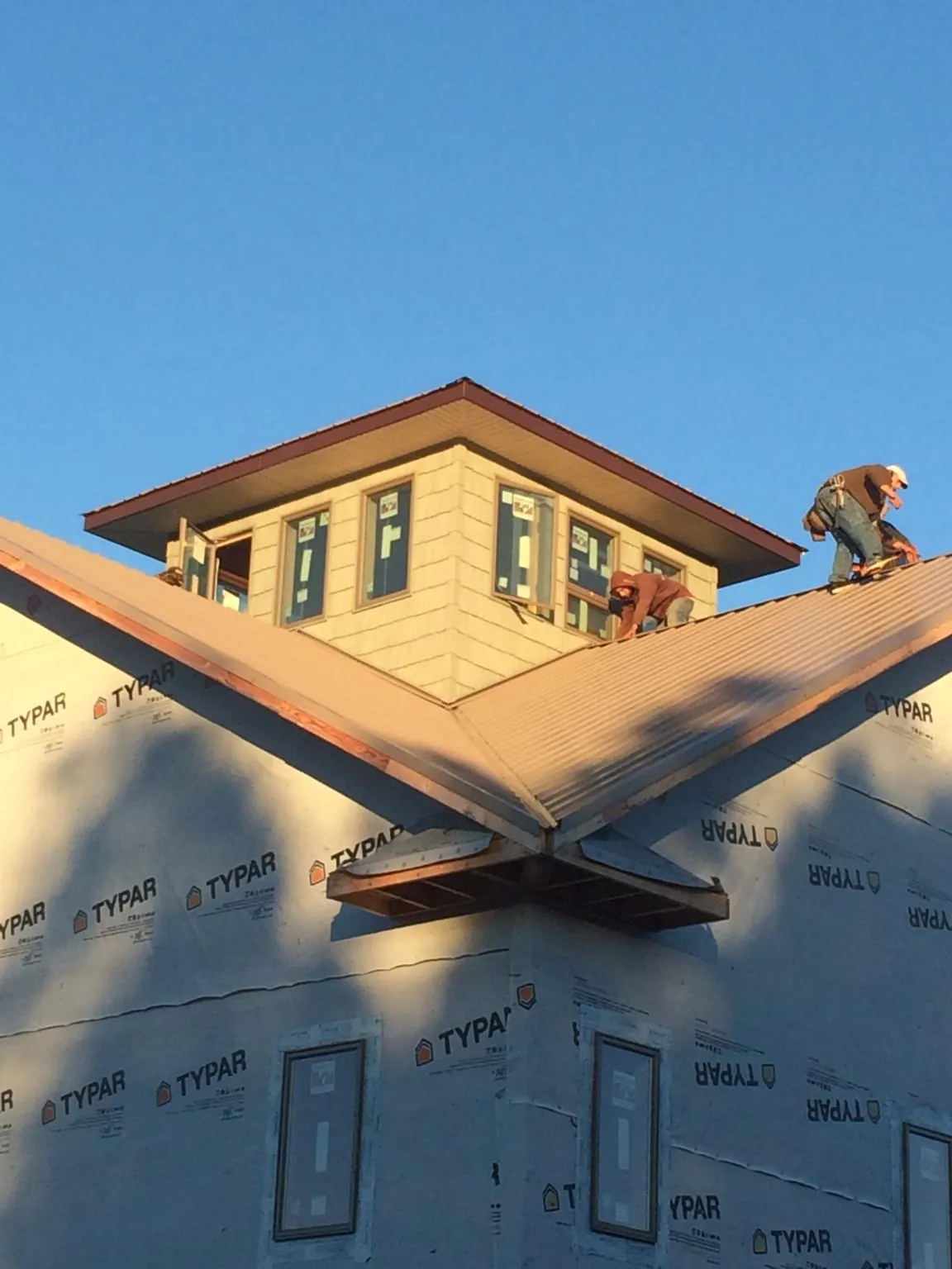 Roofers working around a rooftop cupola on a new metal roof at sunset — Roof Waterproofing in Mendenhall by Roofing Brothers
